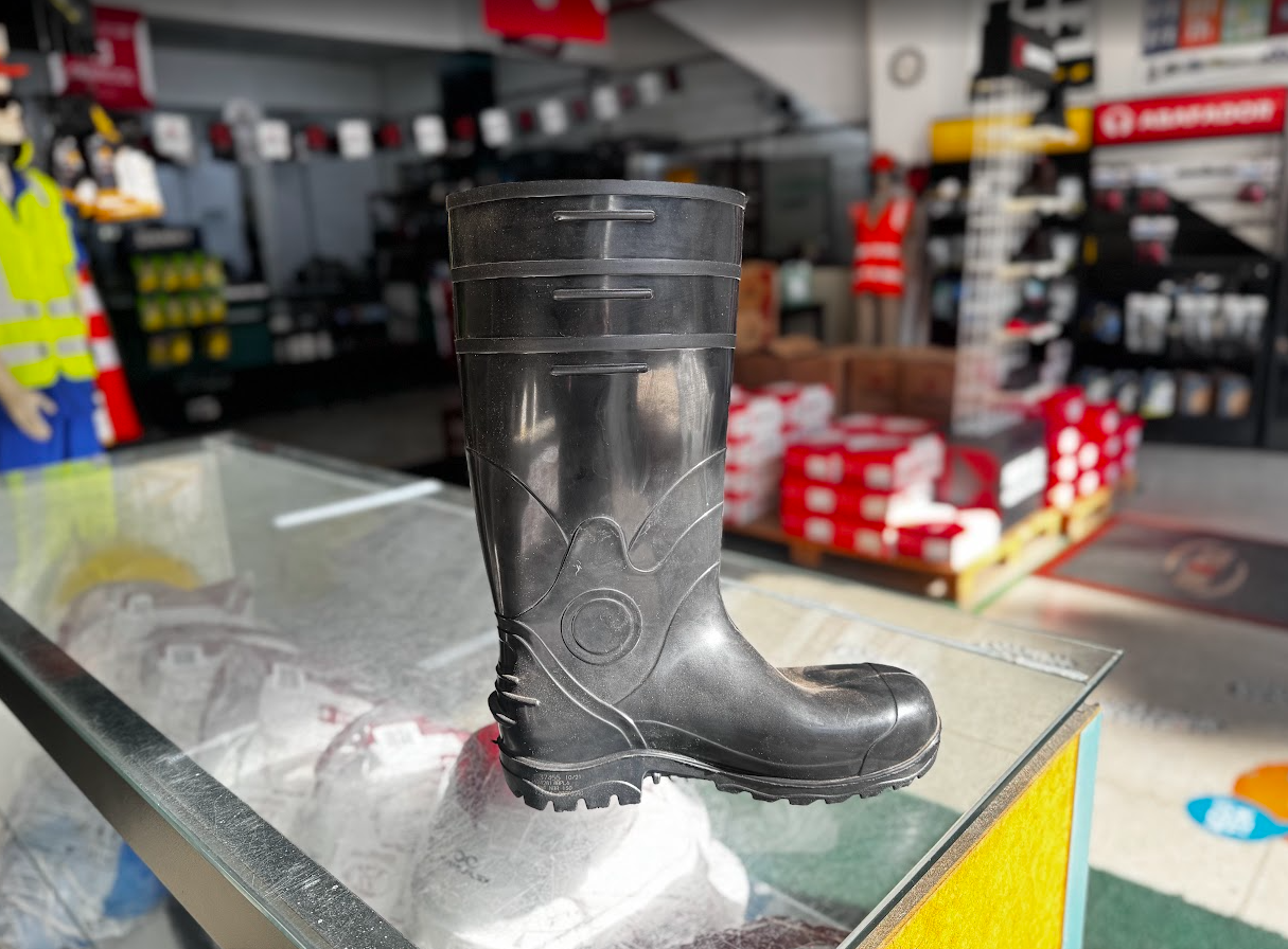 Bota de PVC preta de cano alto em destaque no balcão da loja Cobequi